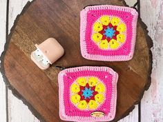 two crocheted coasters sitting on top of a wooden table next to a camera