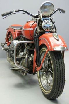 an orange motorcycle parked on top of a gray floor