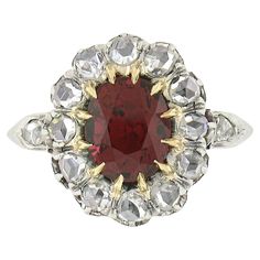 This truly breathtaking antique ring was crafted during the Victorian era from solid 18k yellow gold with a platinum top. It features an elegant flower cluster design set with a, GIA certified, natural spinel stone at its center. This gorgeous gemstone has an oval brilliant cut and displays the most gorgeous vivid red color with NO HEAT indications, bringing a truly attractive and desirable look to this piece. It is surrounded by a halo of 12 old rose cut diamonds with an additional 2 at the sid Classic Ruby Ring With Rose Cut Diamond Cluster, Red Oval Cluster Ring With Rose Cut Diamonds, Formal Ruby Cluster Ring With Rose Cut Diamonds, Formal Red Diamond Ring With Rose Cut Diamonds, Heirloom Red Oval Cluster Ring, Antique Red Diamond Ring With Rose Cut Diamonds, Victorian Oval Red Diamond Ring, Vintage Brilliant Cut Cluster Ruby Ring, Vintage Cluster Ruby Ring With Brilliant Cut