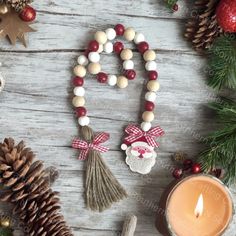 a candle and some christmas decorations on a wooden table with pine cones, candles and ornaments