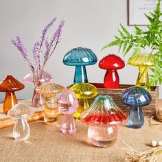 there are many different colored glass vases on the table