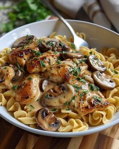 pasta with chicken, mushrooms and parsley in a white bowl on a wooden table