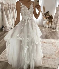 a woman taking a selfie while wearing a wedding dress in front of a mirror