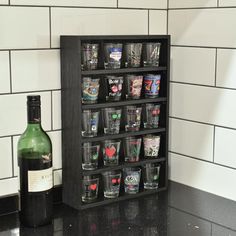 a bottle of wine sitting on top of a counter next to shot glasses and a glass holder