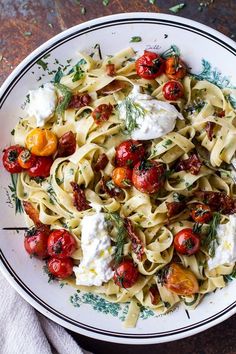 a plate of pasta with tomatoes, fettuccine and goat cheese on top