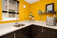 a kitchen with yellow walls and white counter tops, black cabinetry, and brown cabinets