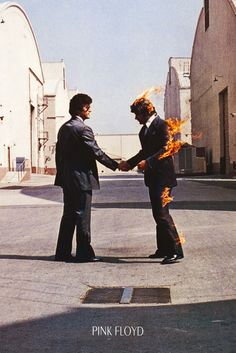 two men in suits shaking hands with each other on the street, one holding fire