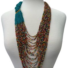 This beautiful beaded necklace features a long, red braided intricate beadwork. Its design reflects the traditional aesthetic of African fashion, with a touch of modern style. The hook closure secures the necklace in place, making it a convenient accessory to wear for any occasion. The vibrant green colour adds an eye-catching element to any outfit, while the beaded fringe adds a unique and elegant touch. This necklace is perfect for those who appreciate the beauty and cultural significance of African jewellery.  Colour - Green and Multicolours *Brass metal connectors  Total inner length - 22inches/56cm Hand-strung Multicolor Beaded Lariat Necklace, Artisan Multi-strand Faceted Beads, Red Long Beaded Necklace Hand-strung, Red Multi-strand Beaded Necklace, Red Hand-strung Long Beaded Necklace, Multi-strand Red Necklace With Colorful Beads, Red Long Hand-strung Beaded Necklace, Multi-strand Beaded Necklace With Large Beads, Artisan Multi-strand Beaded Chain