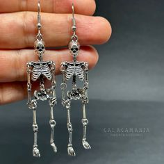 Get ready to dance the night away with these one-sided skeleton earrings in a vintage metallic silver finish! Perfect for any occasion - Halloween, Day of the Dead, a birthday party, or a night out with friends. Lightweight, articulated (all limbs are movable) and beautifully detailed, these earrings make a unique and original gift for yourself or someone special. Add some gothic, punk, and tattoo fashion to your look with these playful and quirky CALACAMANIA™ accessories Earrings details: Size: Skull-shaped Metal Earrings, Silver Skull Earrings For Halloween, Metal Halloween Party Jewelry, Gothic Skull Metal Earrings, Bone Colored Metal Earrings For Pierced Ears, Punk Style Hand Cast Halloween Jewelry, Skull Jewelry For Day Of The Dead Party, Skull Shaped Jewelry For Day Of The Dead Party, Nickel-free Skull Jewelry For Party