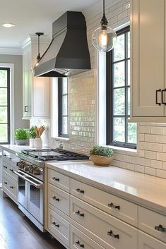 a large kitchen with white cabinets and black hood over the stove, along with two windows