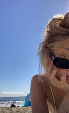 a woman on the beach talking on her cell phone