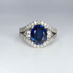 Oval Blue Sapphire and Moissanite 3 Stone Split Shank Halo Ring 14K solid Gold, Blue Sapphire Engagement Ring, September Birthstone, #8143 #BlueStoneRing #EngagementRing #BlueSapphire #SplitShankRing #Moissanite3Stone #14kSolidGold #HaloRing #SomethingBlue #SeptemberBirthstone #OvalBlueSapphire Blue Oval Gia Certified Halo Ring, Blue Sapphire Gemstone With Center Stone, Gia Certified Tanzanite Sapphire Rings, Gia Certified Blue Oval Rings, Gia Certified Blue Round Gemstones, Gia Certified Round Blue Gemstones, Gia Certified Oval Blue Gemstones, Oval Blue Gemstones With Halo Setting, Oval Blue Sapphire Ring With Vvs Clarity