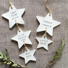 four ceramic star ornaments with names hanging from twine strings on a linen tablecloth