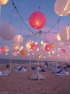 an instagram page on the beach with paper lanterns in the sky and people sitting under them