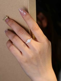 a close up of a person's hand with a diamond ring on their finger