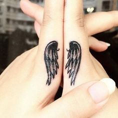 two hands with black angel wings on their fingers and one is holding the other's hand