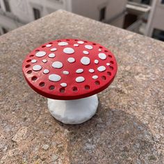 a red and white mushroom sitting on top of a stone table next to a building