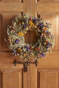 a wreath hanging on the front door of a house with flowers all over it,