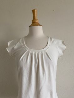 Womens short sleeve tshirt. This is a cute little tee with raglan cap sleeves. It has pleats in front with a scoop neck. It is loose and flowy and is made with my favorite soft stretchy cotton jersey knit.  Length from shoulder to hem size Small is 24", length increases 1/2" each size up (note the length can be adjusted as needed) Shown in Off White See Swatch Chart in the last photo for available Color options. Garments are Made To Order Please allow 7-10 days for your item to be sewn Below are my standard size measurements, which are simply a guideline, if you would like to include your personal measurements in the notes to seller box during checkout, I will be sure to make you the best fit ~ if you have any questions feel free to ask :)  BASIC SIZING   XSmall 0-2 Bust 33-34, Waist 25-26 Loose Fit Shirts, Scoop Neck Top, Knitted Tshirt, Caps For Women, Jersey Tee, Cotton Knit, Short Sleeve Blouse, Cap Sleeve, Stretch Cotton