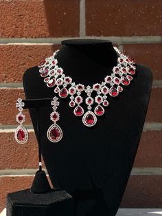 Handmade Style: Necklace and Earrings Set Material: Platinum Plated, Lab Simulated Ruby and White Sapphire Stones Imported Please Note: This necklace and earrings are sold as a set. Item Number: 6700R Teardrop Jewels Jewelry For Formal Occasions, Formal Teardrop Jewels Jewelry, Luxury Red Pear-shaped Jewelry, Formal Ruby Drop Jewelry, Elegant Ruby Jewelry Sets With Matching Earrings, Teardrop Costume Jewelry For Formal Occasions, Red Drop Jewelry For Formal Occasions, Evening Ruby Jewelry With Matching Earrings, Evening Ruby Jewelry Set With Matching Earrings