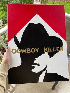 a person holding up a sign that says cowboy killer