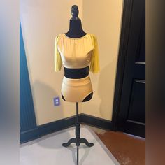 a mannequin with a yellow top and black bottom on display in a room