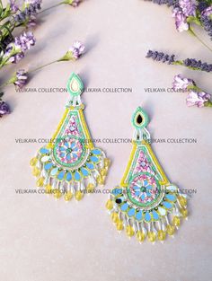 a pair of colorful earrings sitting on top of a table next to purple flowers and lavenders