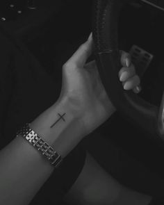 a woman driving a car with a cross tattoo on her wrist