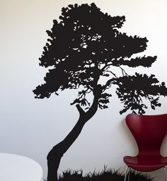 a black tree on the wall next to a red chair and table with a white table