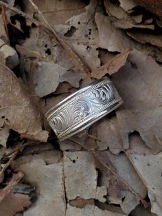 a silver ring sitting on top of leaves