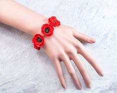 red flowers are attached to the wrist of a mannequin's hand on a white surface