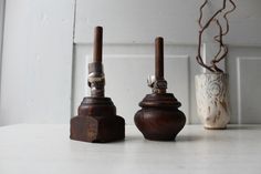 two wooden vases sitting next to each other on a white counter top with a plant in the background