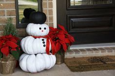 a snowman made out of pumpkins and poinsettis on the front porch