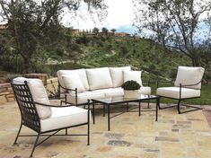 an outdoor patio furniture set with white cushions and black metal frame, sitting on a stone patio