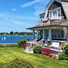 a large house sitting on top of a lush green field next to a body of water