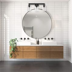 a bathroom with two sinks and a large round mirror on the wall next to it