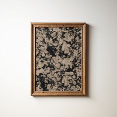 an abstract painting hangs on the wall next to a wooden frame with black and white paint