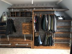 a closet with clothes hanging on rails and shelves in the corner, next to a brick wall