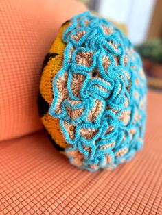 a crocheted ball sitting on top of an orange couch