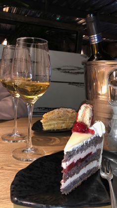 a piece of cake and two glasses of wine on a table