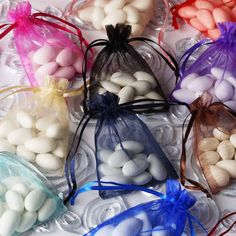 several bags filled with white and pink candy beans on top of a glass tablecloth