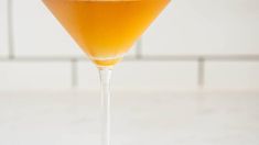 a close up of a drink in a wine glass on a table with white tiles