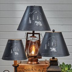 three lamps are sitting on top of an old box with a bear and tree design