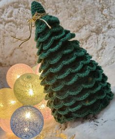 a crocheted christmas tree ornament sitting on top of snow covered ground