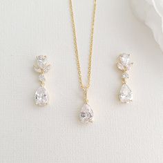 three pieces of jewelry sitting on top of a white table next to a rose flower