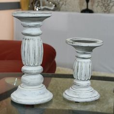 two white candlesticks sitting on top of a glass table