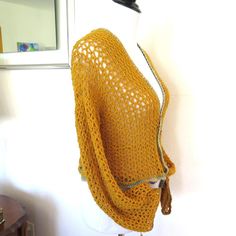 a yellow knitted shawl hanging on a wall next to a mirror and table