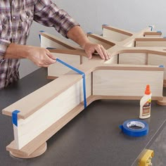 a man is working on woodworking with blue tape and glue around the edge of some pieces