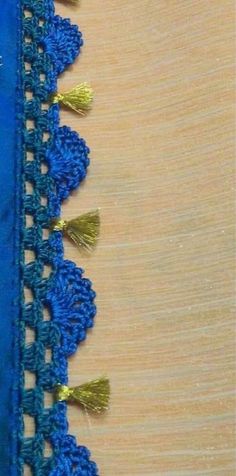 blue crocheted lace with gold tassels on wooden surface