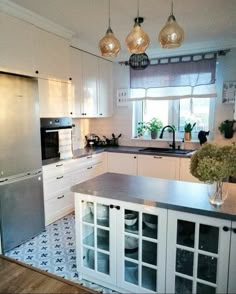 a kitchen with white cabinets and stainless steel appliances in the center, along with black and white tile flooring